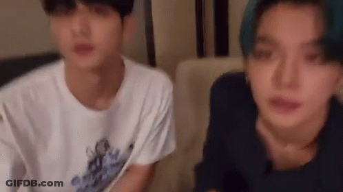 Two Young Men Are Sitting Next To Each Other On A Couch And Looking At Each Other . GIF