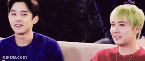 Two Young Men Are Sitting Next To Each Other On A Couch And One Has Green Hair GIF
