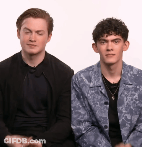 Two Young Men Are Sitting Next To Each Other With One Wearing A Floral Jacket GIF
