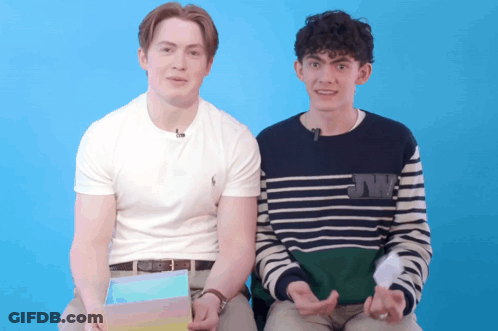 Two Young Men Are Sitting Next To Each Other With One Wearing A Sweater That Says Jw On It GIF