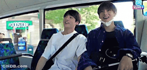 Two Young Men Are Sitting On A Bus In Front Of A Foodstore . GIF