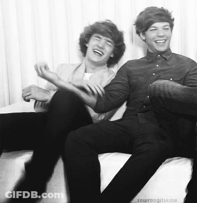Two Young Men Are Sitting On A Couch Laughing Together . GIF