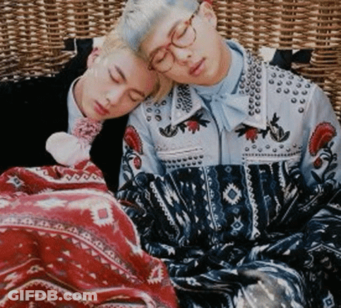 Two Young Men Are Sleeping On A Wicker Couch With Their Heads On Each Other . GIF