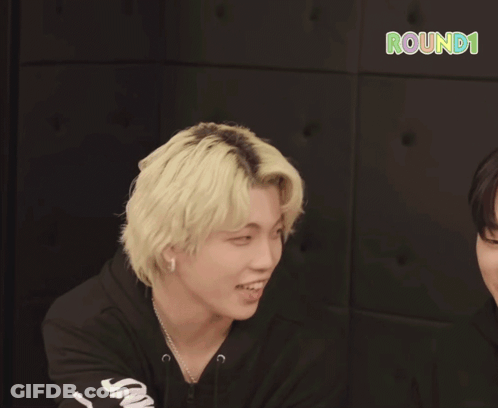 Two Young Men Are Smiling In Front Of A Sign That Says Round 1 On It GIF