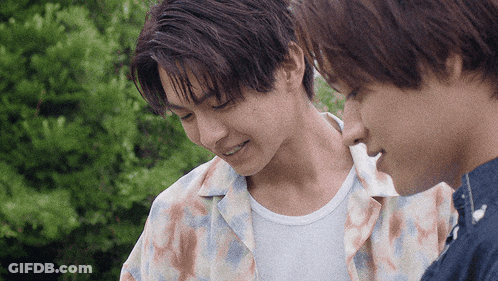 Two Young Men Are Standing Next To Each Other And One Is Smiling GIF