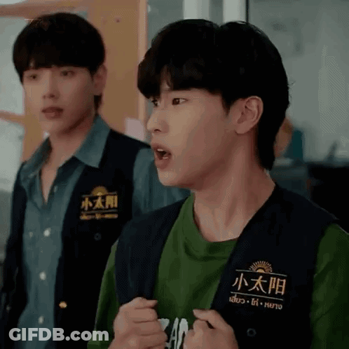 Two Young Men Are Standing Next To Each Other And One Is Wearing A Vest With Chinese Writing On It . GIF