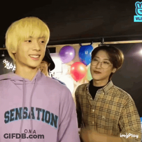 Two Young Men Are Standing Next To Each Other And One Of Them Is Wearing A Purple Hoodie That Says Sensation On It . GIF