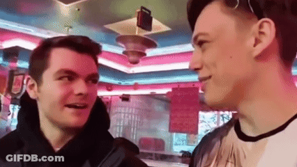 Two Young Men Are Standing Next To Each Other In A Diner Talking To Each Other . GIF