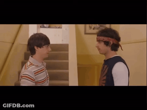 Two Young Men Are Standing Next To Each Other In A Hallway GIF