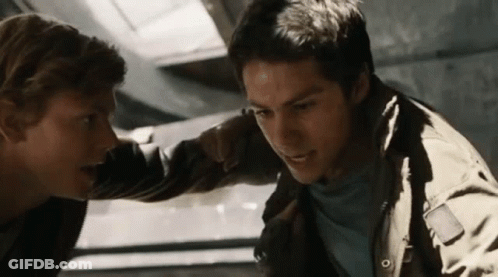 Two Young Men Are Standing Next To Each Other In A Room And Looking At Each Other . GIF