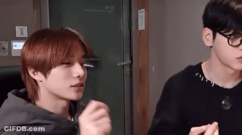 Two Young Men Are Standing Next To Each Other In A Room . GIF