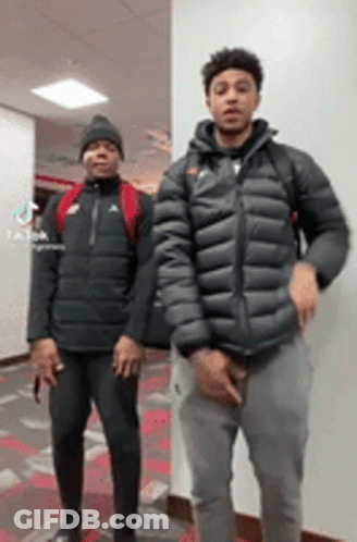 Two Young Men Are Standing Next To Each Other In A Room . GIF