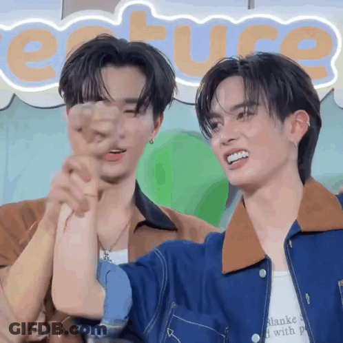 Two Young Men Are Standing Next To Each Other In Front Of A Sign That Says Ecture GIF