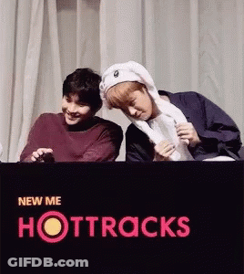 Two Young Men Are Standing Next To Each Other In Front Of A Sign That Says Hottracks GIF
