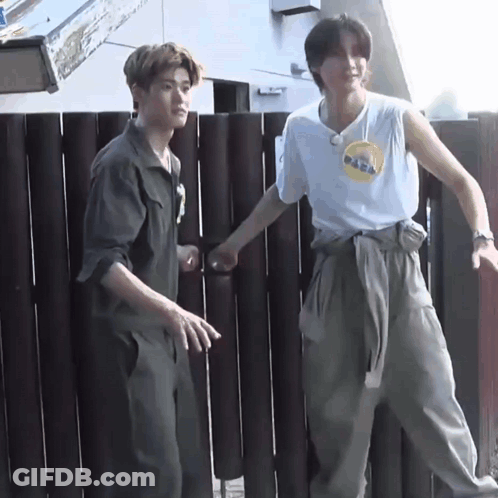 Two Men Standing By Wooden Fence GIF