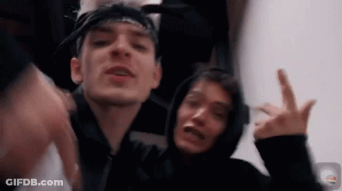Two Young Men Are Standing Next To Each Other Making A Peace Sign . GIF