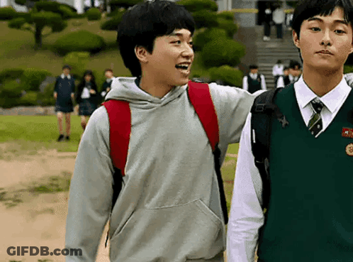 Two Young Men Are Standing Next To Each Other On A Sidewalk . GIF