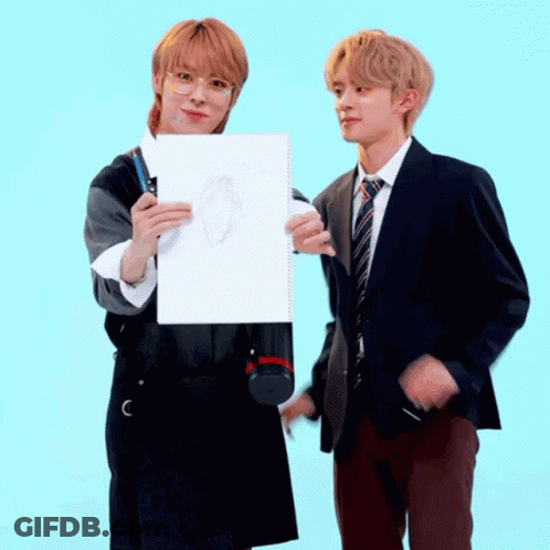 Two Young Men Are Standing Next To Each Other One Is Holding A Drawing GIF