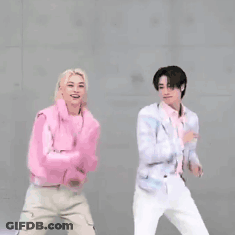 Two Young Men Are Standing Next To Each Other With Their Arms In The Air . GIF