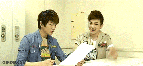 Two Young Men At Table Looking At Papers GIF