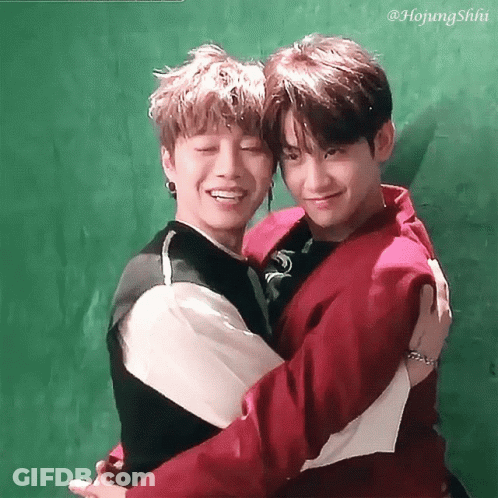 Two Young Men Hugging Each Other With A Green Background GIF