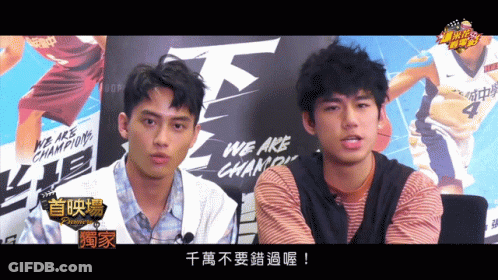 Two Young Men In Front Of We Are Champions Sign GIF