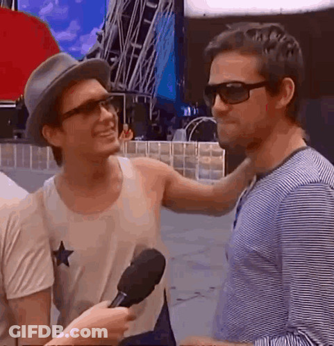 Two Young Men In Front Of We Are Champions Sign GIF