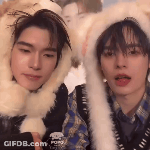 Two Young Men In Furry Hats Looking At Camera GIF