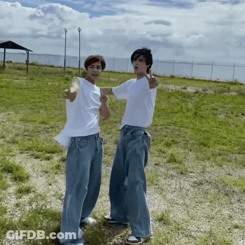 Two Young Men In Grassy Field GIF