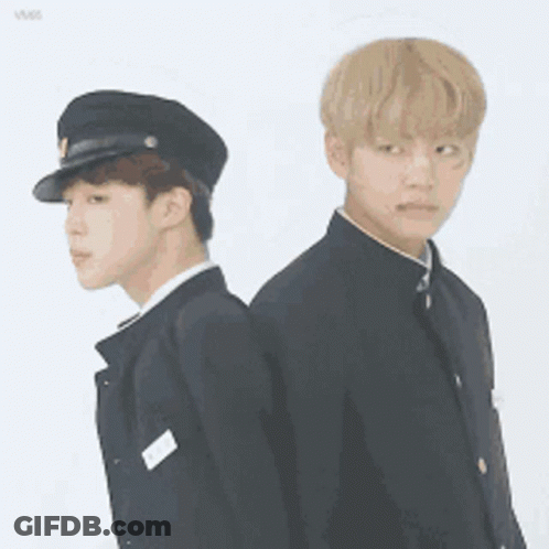 Two Young Men In Uniforms Are Standing Back To Back And One Is Wearing A Hat . GIF