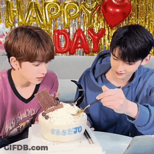 Two Young Men Looking At Cake With Happy Day Balloons GIF