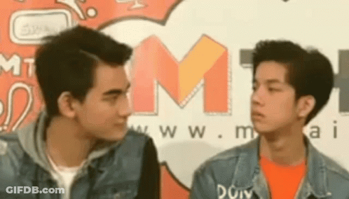 Two Young Men Looking At Each Other In Front Of M1 Sign GIF