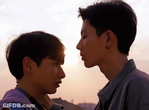 Two Young Men Looking At Each Other One With Earrings GIF
