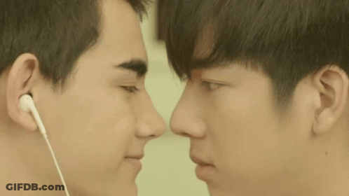 Two Young Men Looking At Each Other Wearing Earbuds GIF