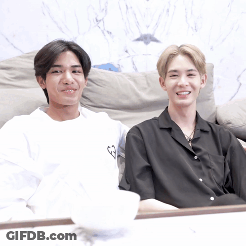 Two Young Men On Couch, One In White Heart Shirt GIF