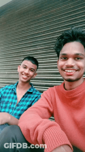 Two Young Men Posing For A Picture With One Wearing A Red Sweater GIF