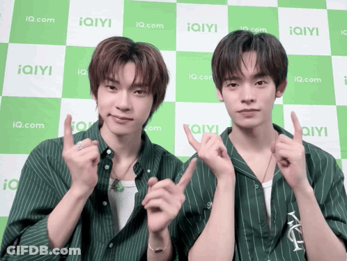 Two Young Men Posing In Front Of IQ.com Checkered Background GIF