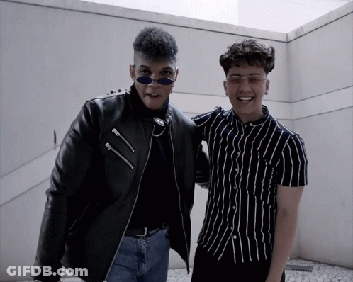 Two Young Men Posing One In Black Jacket GIF