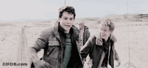 Two Young Men Running In Desert Holding Hands GIF
