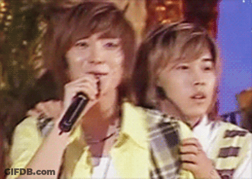 Two Young Men Singing Into Microphones While One Has A Headset On GIF