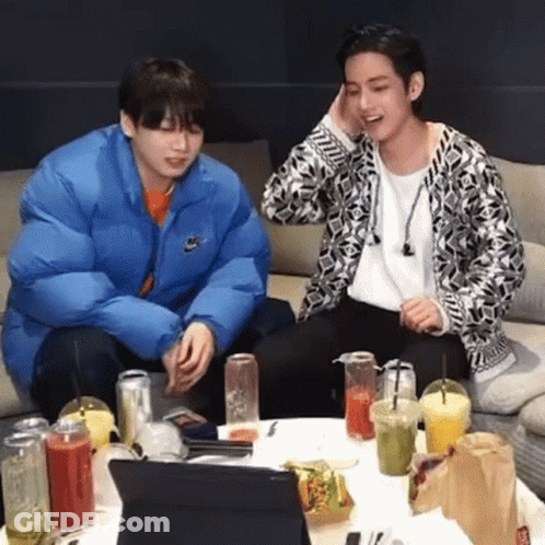 Two Young Men Sitting At Table With Drinks And Laptop GIF