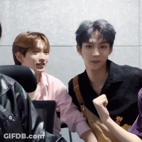 Two Young Men Sitting Next To Each Other One In Pink Shirt GIF