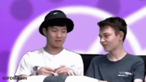Two Young Men Sitting On Couch Looking At Each Other GIF