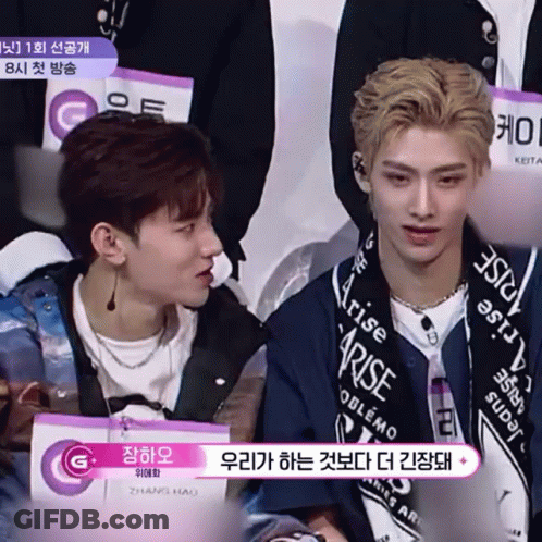 Two Young Men Sitting, One In Blue Rise Jacket GIF