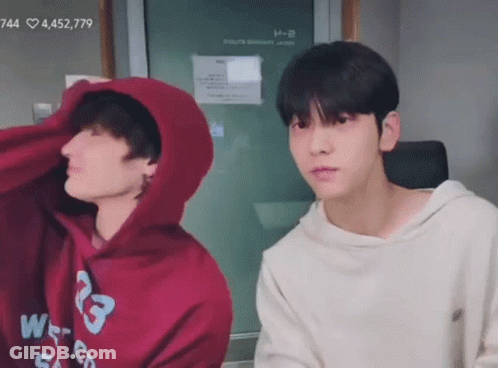 Two Young Men Sitting, One In Hoodie GIF
