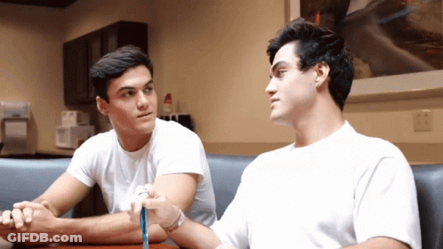 Two Young Men Sitting With Crossed Arms GIF