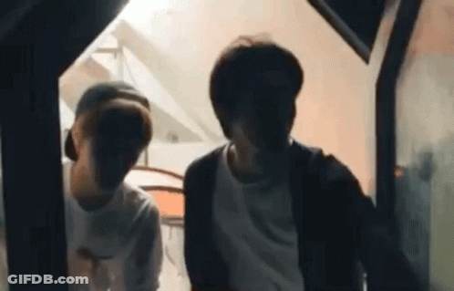 Two Young Men Standing In Dark Room GIF