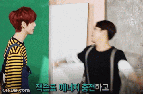 Two Young Men Standing In Front Of Green And White Wall One Red Hair One Blonde GIF