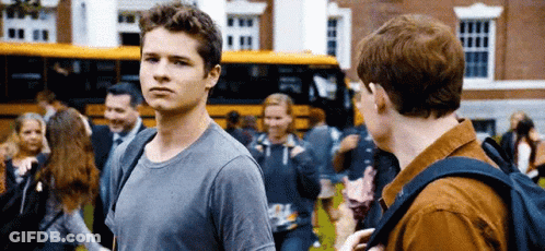 Two Young Men Standing In Front Of School Bus Talking GIF