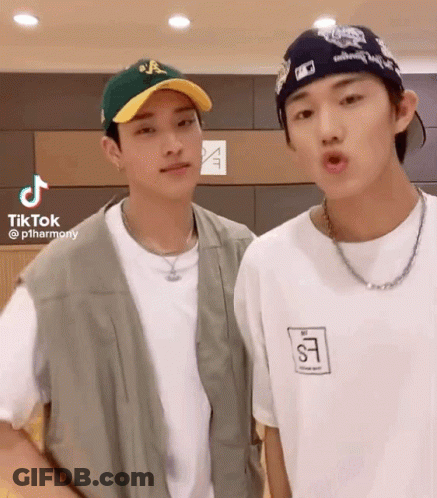 Two Young Men Standing Next To Each Other Wearing Hats And Shirts GIF